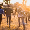 young adults run through the desert toward the setting sun